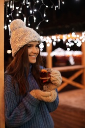 Photo of Woman with glass cup of mulled wine at winter fair