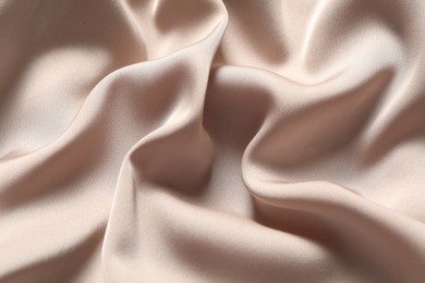 Texture of beige crumpled silk fabric as background, closeup