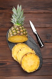 Photo of Pieces of tasty ripe pineapple on wooden table, top view