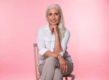 Portrait of beautiful mature woman on pink background