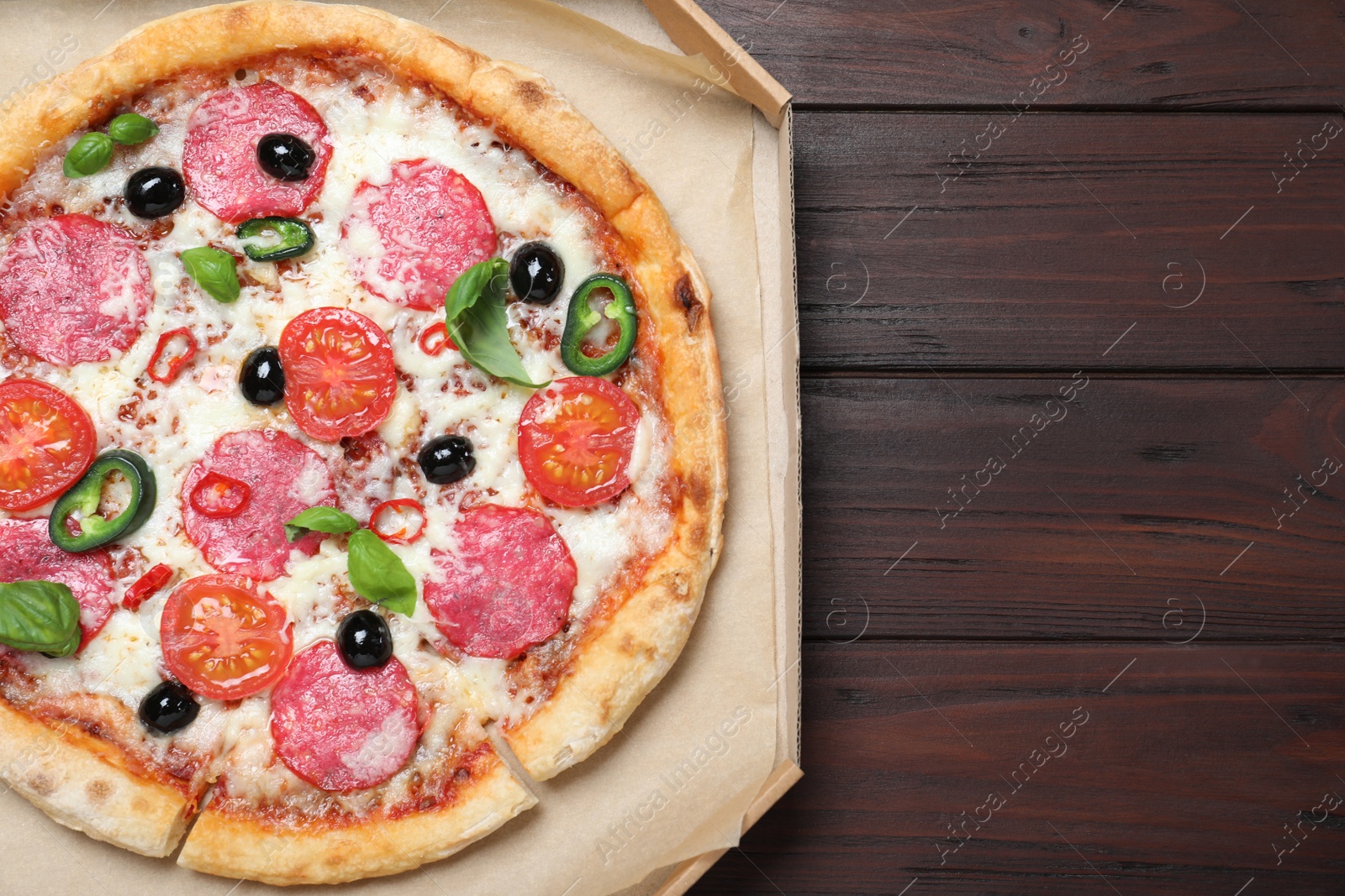 Photo of Delicious pizza Diablo in cardboard box on wooden background, top view. Space for text