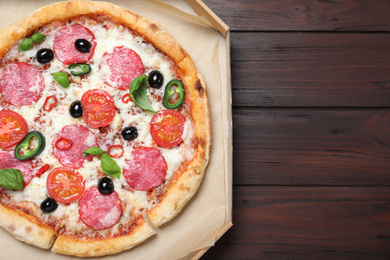 Delicious pizza Diablo in cardboard box on wooden background, top view. Space for text