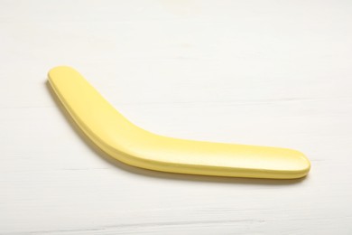 Yellow boomerang on white wooden background. Outdoors activity