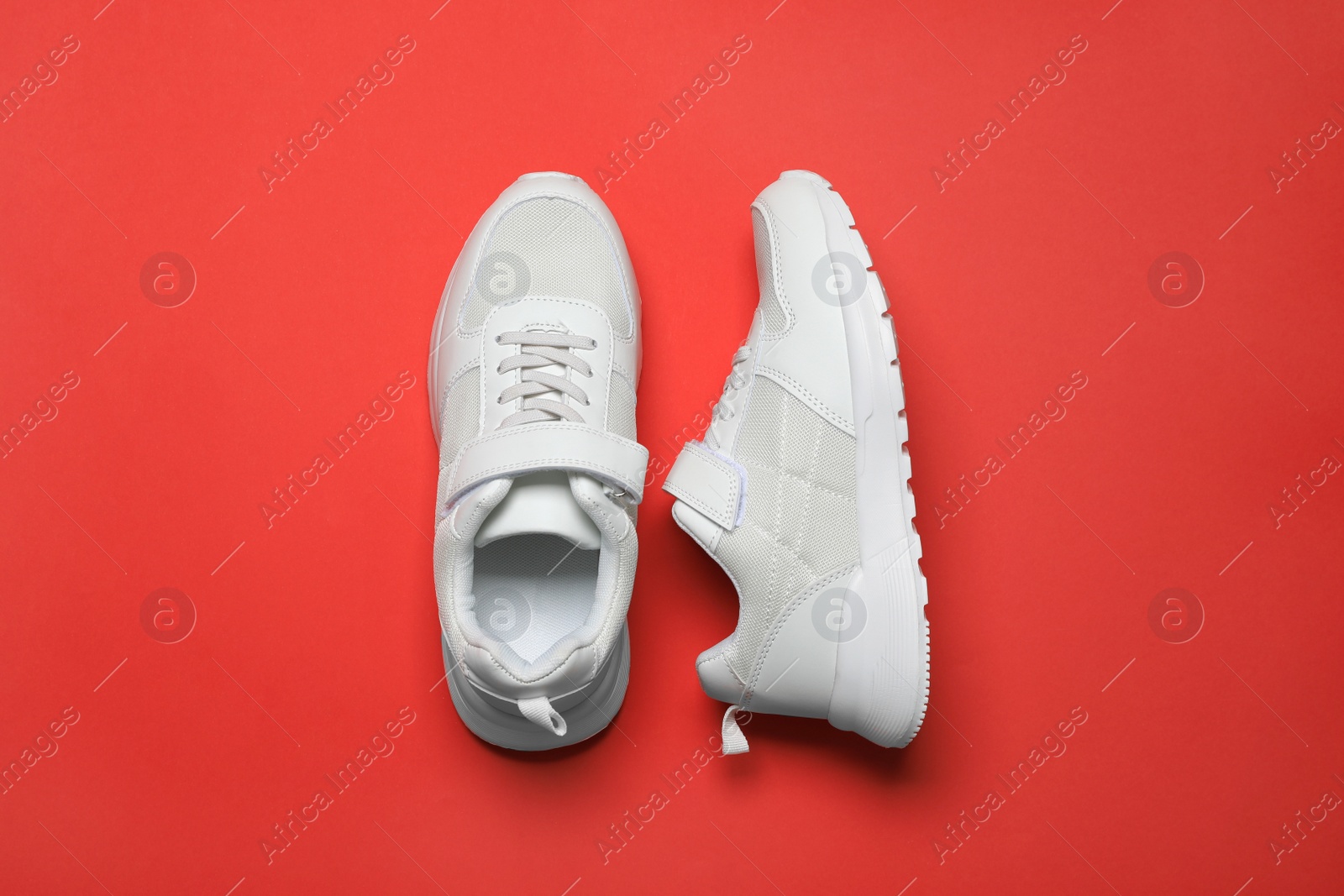 Photo of Pair of comfortable sports shoes on red background, flat lay