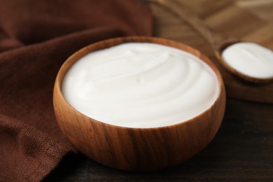 Delicious natural yogurt in bowl on wooden table, closeup