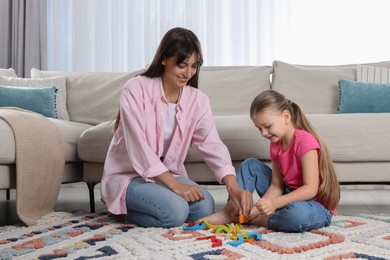 Motor skills development. Mother helping her daughter to play with colorful wooden arcs at home