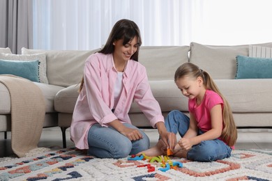 Photo of Motor skills development. Mother helping her daughter to play with colorful wooden arcs at home