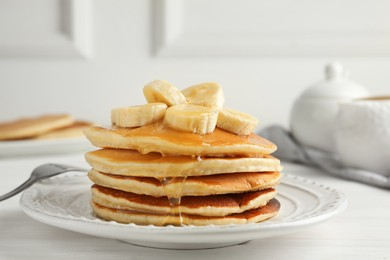 Photo of Delicious pancakes with bananas and honey on white wooden table, closeup