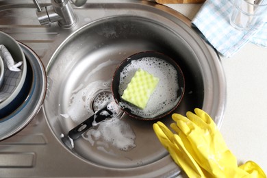 Photo of Dirty frying pan with sponge in kitchen sink, above view