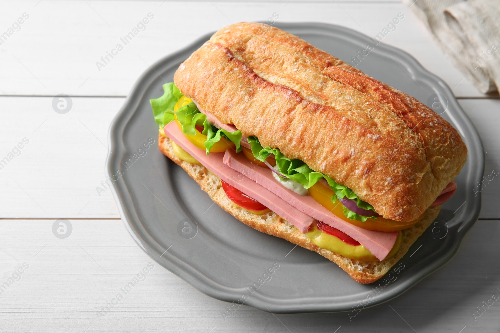 Photo of Tasty sandwich with boiled sausage, cheese and vegetables on white wooden table, closeup