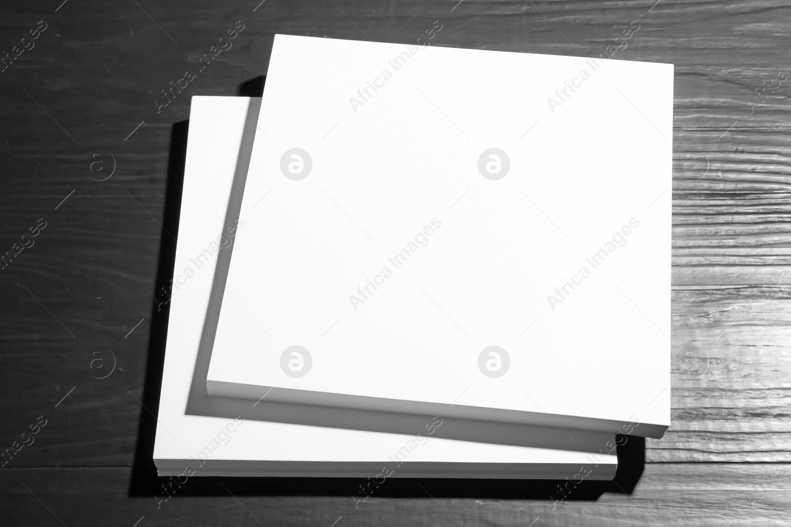 Photo of Stack of blank paper sheets for brochure on black wooden background. Mock up