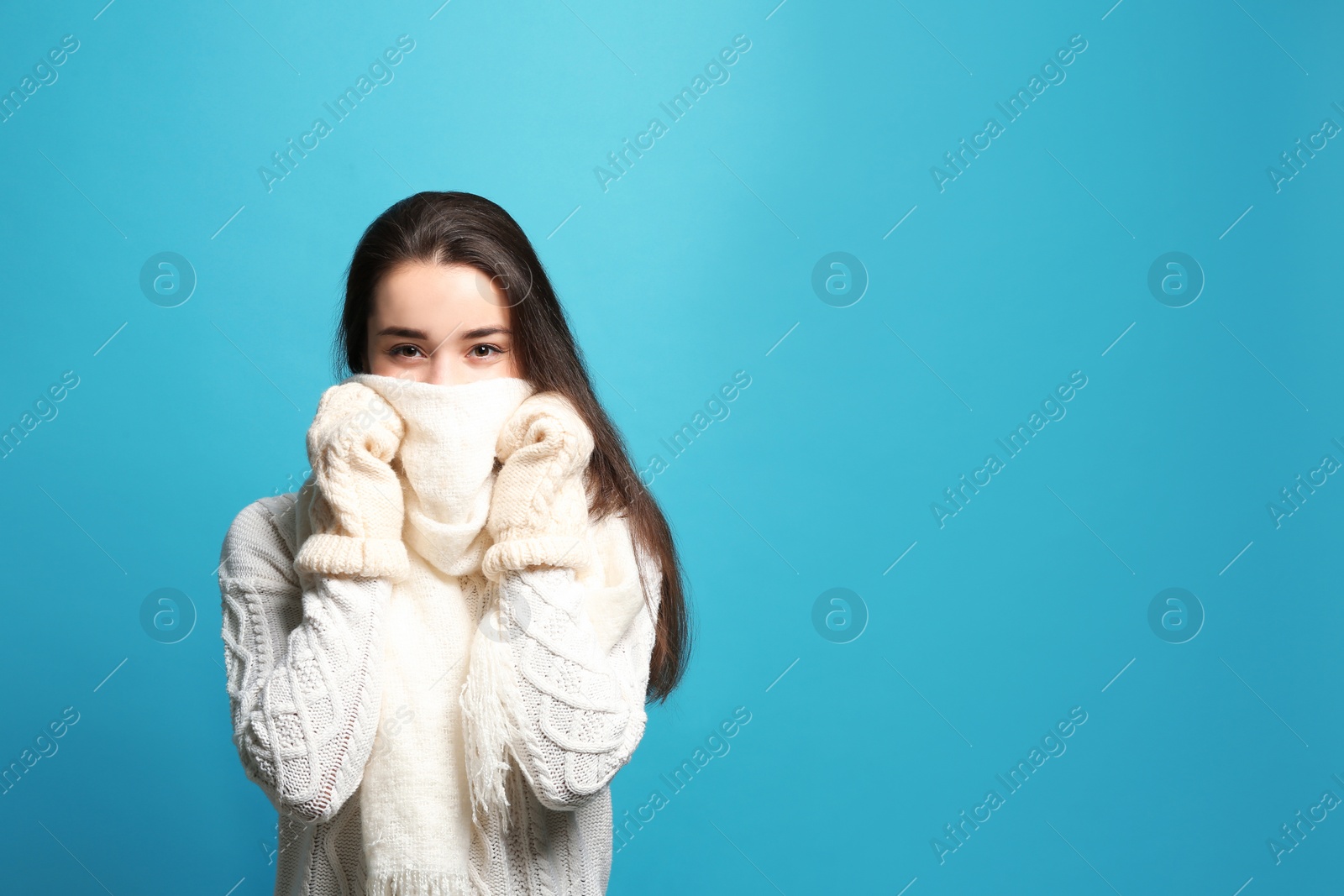 Photo of Young woman wearing warm clothes on color background, space for text. Winter season