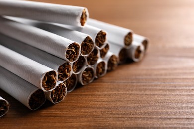 Photo of Pile of cigarettes on wooden table, closeup