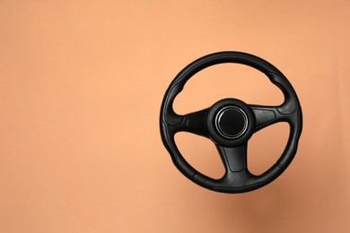 Photo of New black steering wheel on orange background, space for text