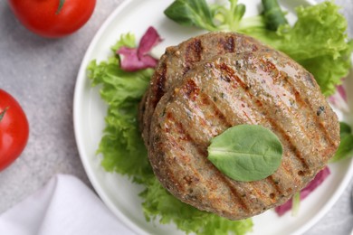 Delicious grilled vegan cutlets and tomatoes on light grey table, flat lay