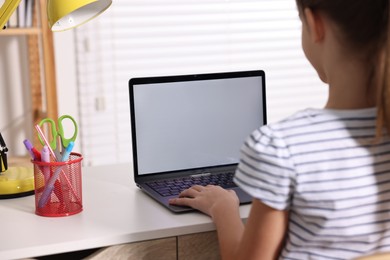 E-learning. Girl using laptop during online lesson at table indoors, closeup