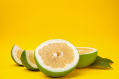 Cut sweetie fruits with green leaves on yellow background. Space for text