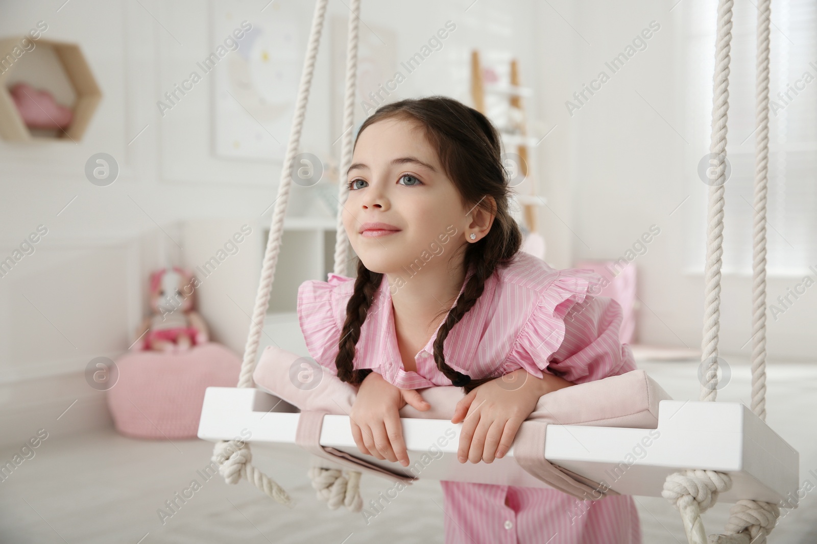 Photo of Cute little girl playing on swing at home