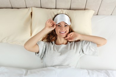 Photo of Beautiful woman with sleep mask in bed, top view