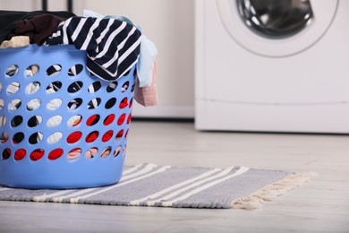 Photo of Plastic laundry basket overfilled with clothes in bathroom. Space for text