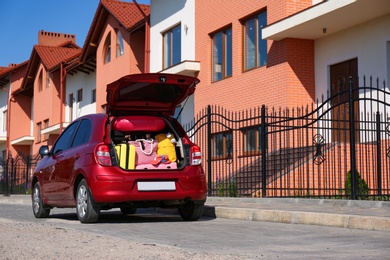 Photo of Family car with open trunk full of luggage in city. Space for text