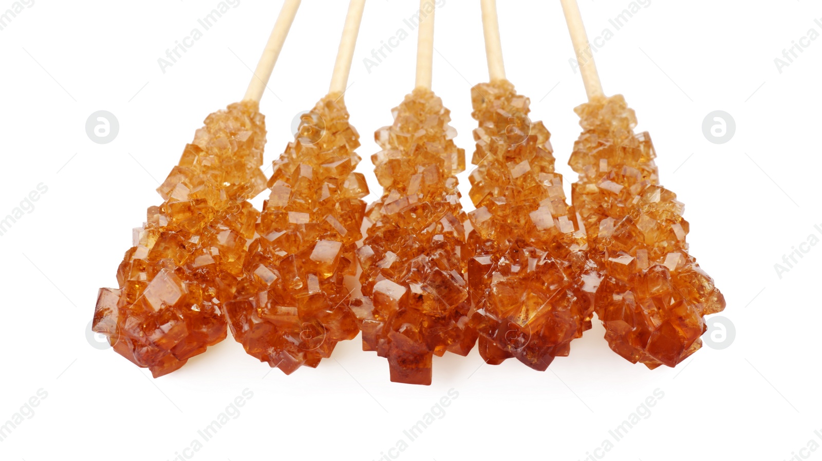 Photo of Wooden sticks with sugar crystals isolated on white, closeup. Tasty rock candies