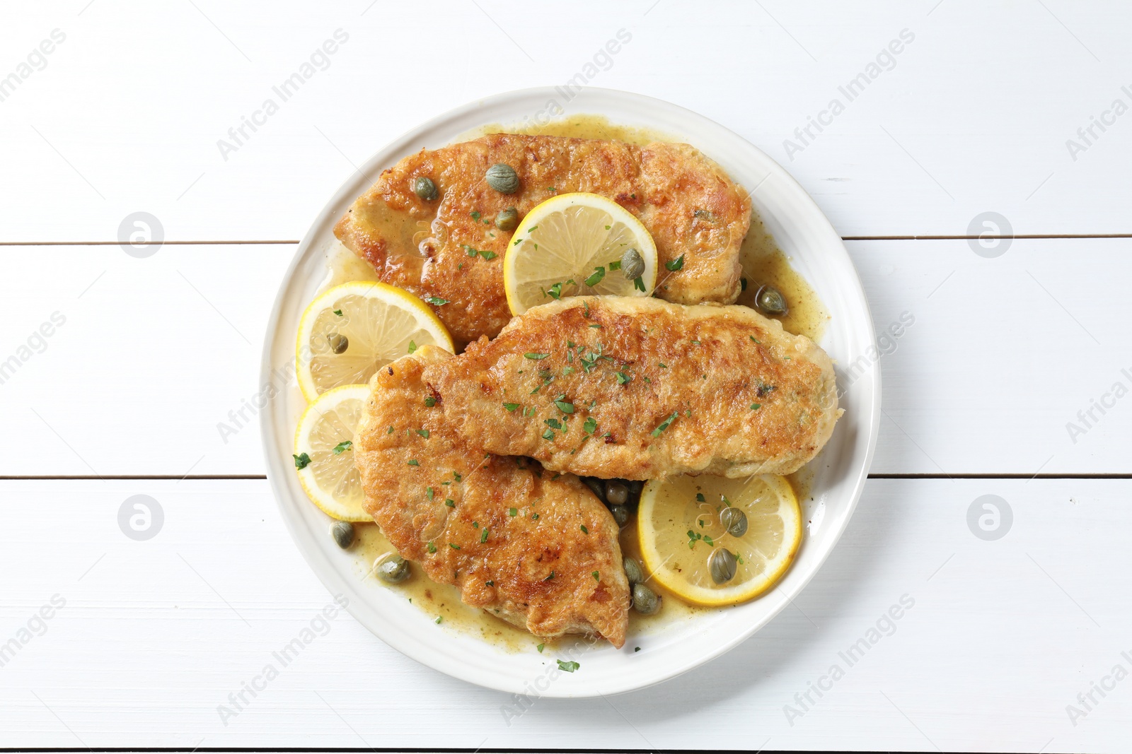 Photo of Delicious chicken piccata on white wooden table, top view