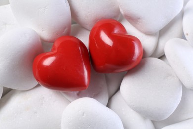 Photo of Decorative hearts on white pebble stones, above view