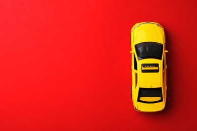 Photo of Yellow taxi car model on red background, top view. Space for text