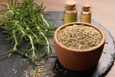 Photo of Essential oil, fresh and dry rosemary on table, closeup
