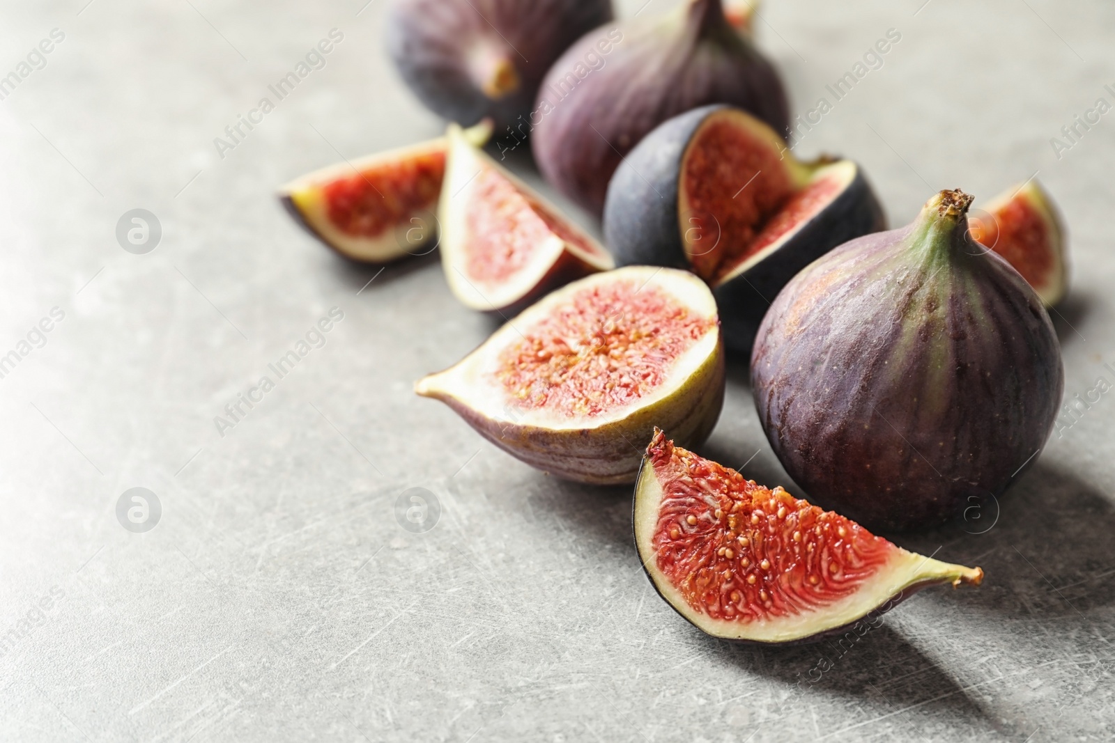 Photo of Whole and cut purple figs on gray background. Space for text