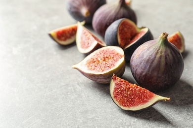 Whole and cut purple figs on gray background. Space for text