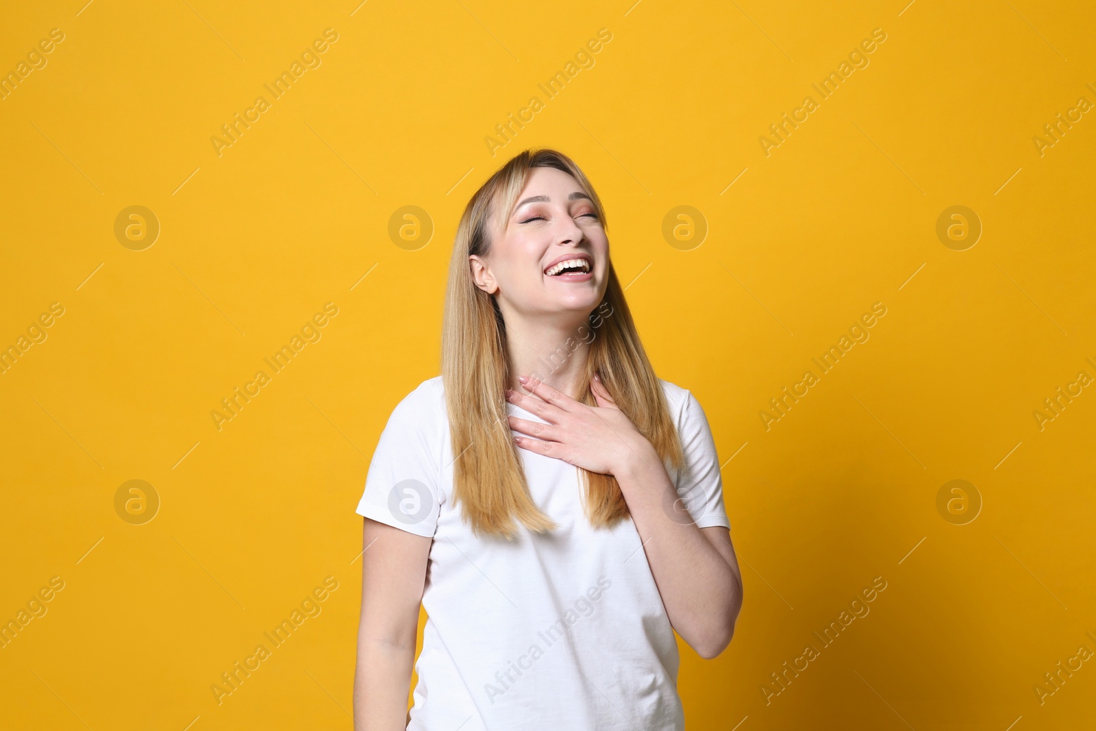 Photo of Beautiful young woman laughing on yellow background. Funny joke