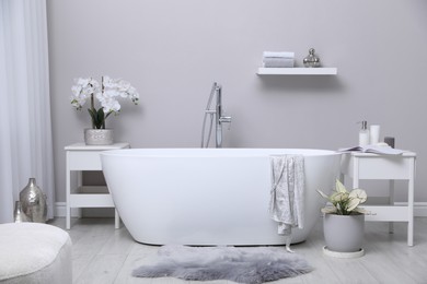 Photo of White tub and beautiful plants in bathroom, Interior design