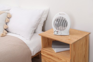 Photo of Modern electric fan heater on bedside table indoors
