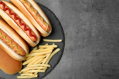 Photo of Delicious hot dogs and french fries on grey background, top view. Space for text