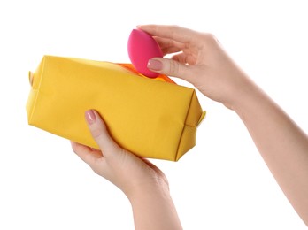 Photo of Woman putting makeup sponge into cosmetic bag on white background, closeup