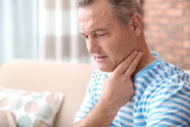 Mature man checking pulse with fingers at home. Space for text