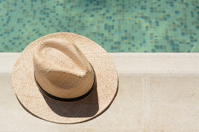 Photo of Stylish hat near outdoor swimming pool on sunny day, space for text. Beach accessory