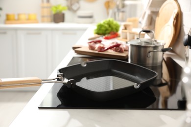 Photo of Frying pan with cooking oil on cooktop in kitchen