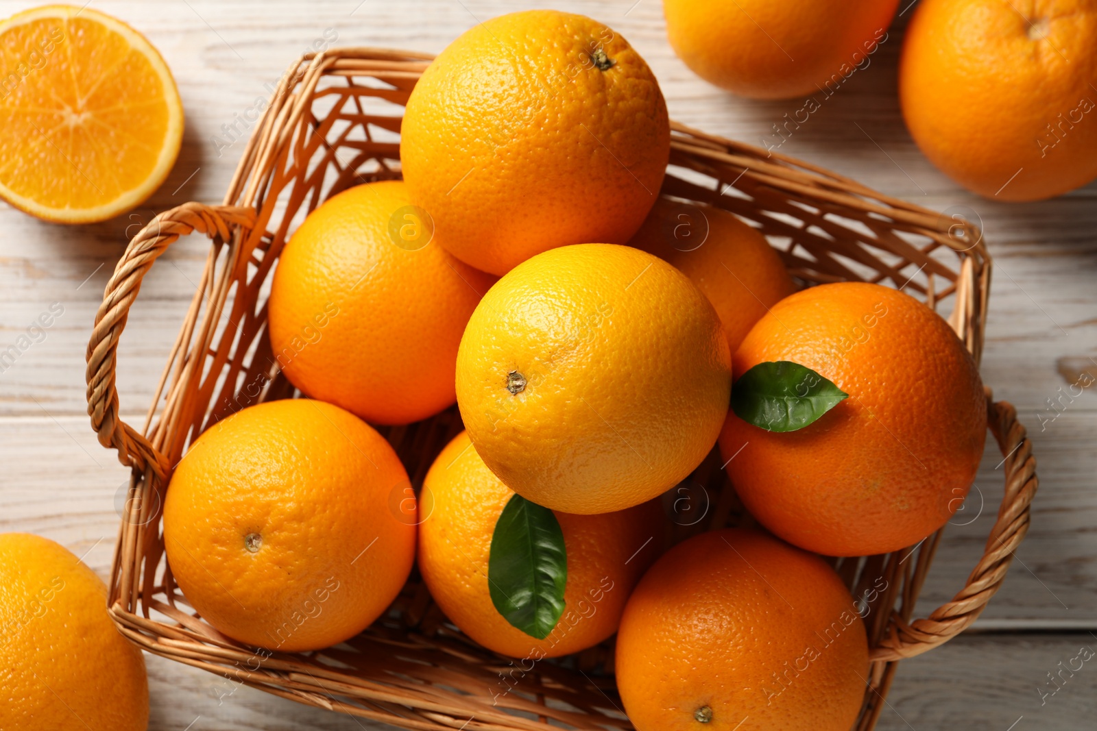 Photo of Many ripe oranges and green leaves on wooden table, top view