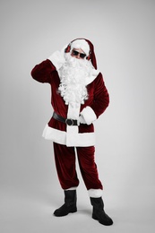 Santa Claus with headphones listening to Christmas music on light grey background