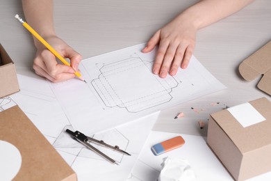 Photo of Woman creating packaging design at light wooden table, closeup