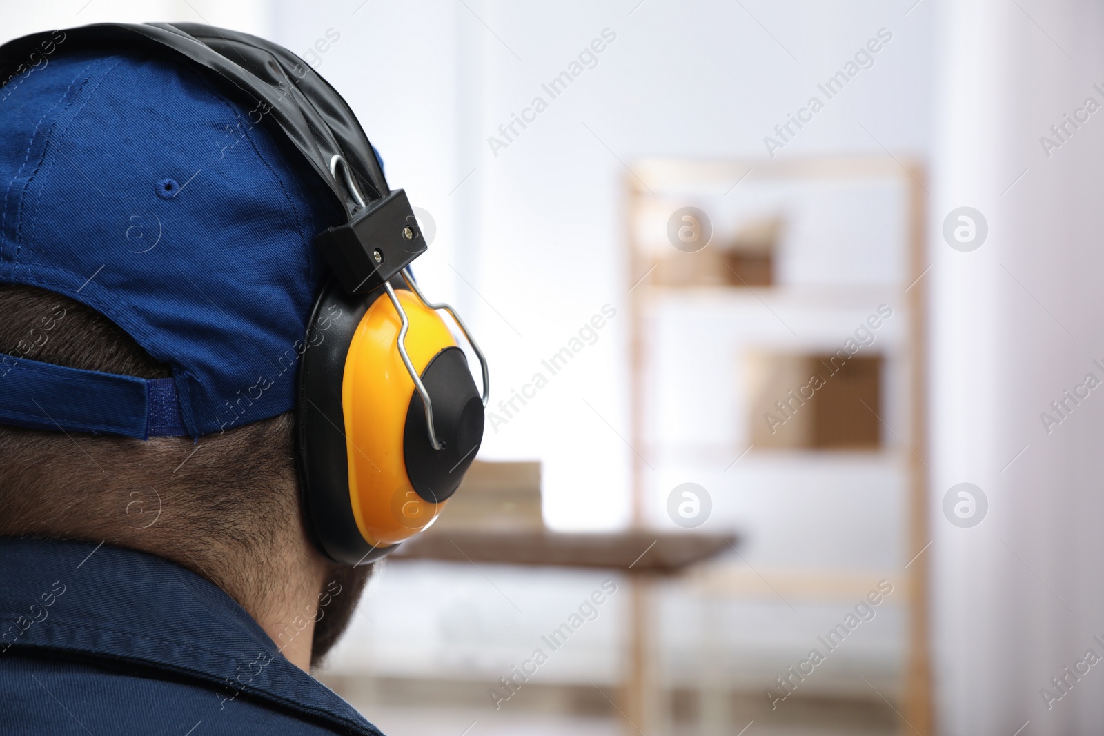 Photo of Worker wearing safety headphones indoors, closeup. Hearing protection device