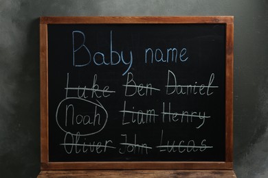 Blackboard with baby names near dark wall