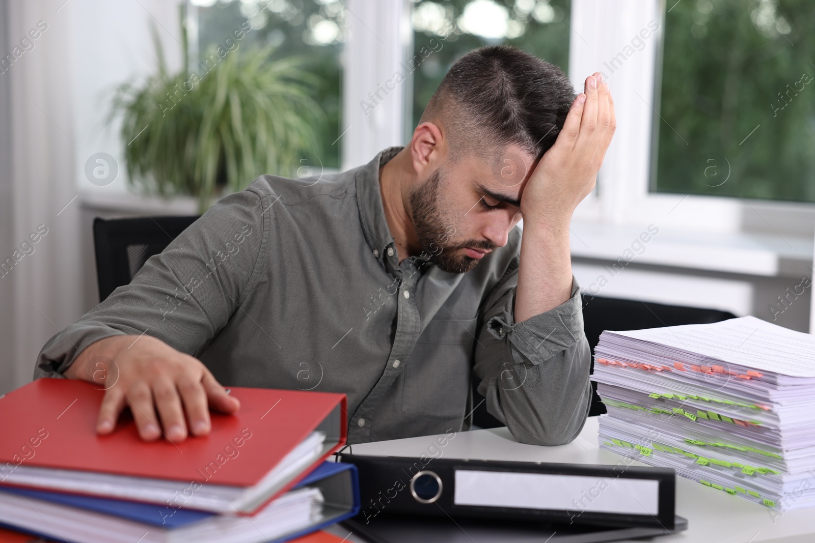 Photo of Overwhelmed man sitting at table with documents in office