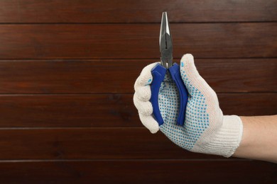 Photo of Man with needle nose pliers on wooden background, closeup. Space for text