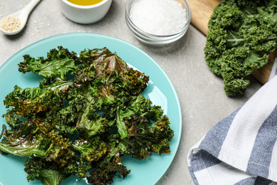 Photo of Tasty baked kale chips on light grey table, above view