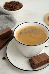 Delicious wafers and cup of coffee for breakfast on white wooden table