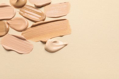 Photo of Samples of skin foundation on beige background, flat lay. Space for text